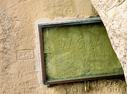 [There is etching of initials and names on the part of rock shown in the image. Clark's signature is protected with a glass-framed lockbox. He signed his name W. Clark.]